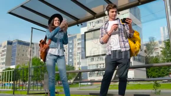 晴天人们站在公共汽车站带着手机在等公共汽车稳定的照相机视频的预览图