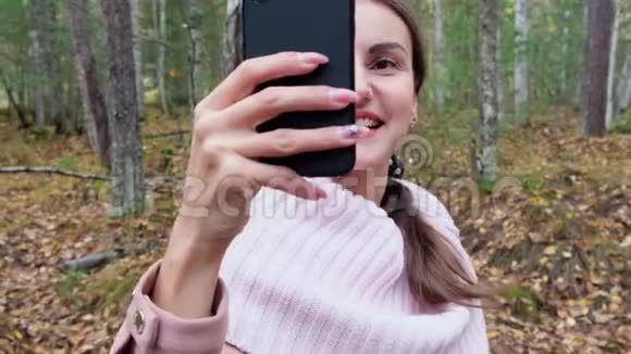 秋林开朗的女性在Skype上打电话女孩在秋天的森林里自拍视频的预览图