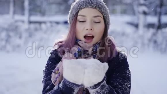快乐的年轻女子对着镜头吹雪冬季体育假日关系爱情圣诞节生活方式视频的预览图