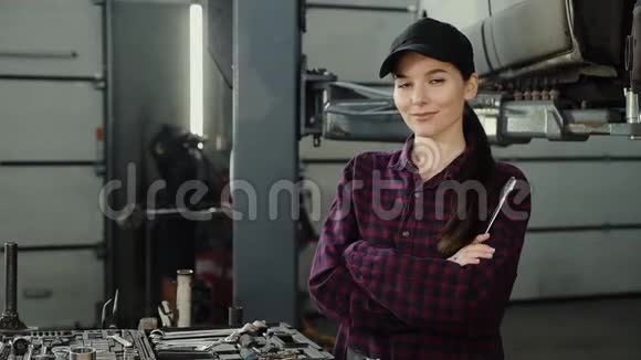 一个漂亮自信的女人在现代汽车修理工工作时拿着一把扳手的肖像视频的预览图