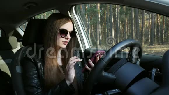 漂亮的女孩在车里用手机视频的预览图