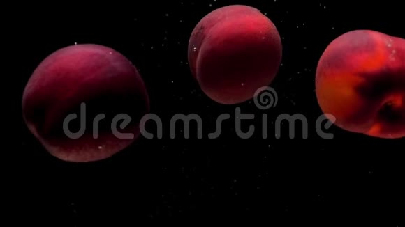 三个熟透的桃子躺在透明的水底下黑色的背景视频的预览图
