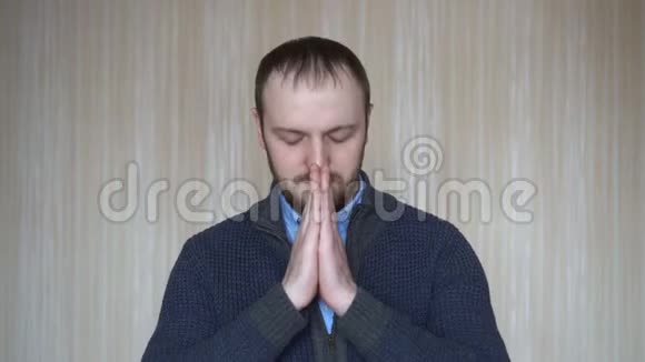 充满希望的年轻留着胡子的男人在祈祷时双手紧握的画像视频的预览图