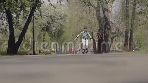 可爱的男孩穿着鲜艳的衣服在河边的公园里滑旱冰户外休闲孩子一个人玩视频的预览图