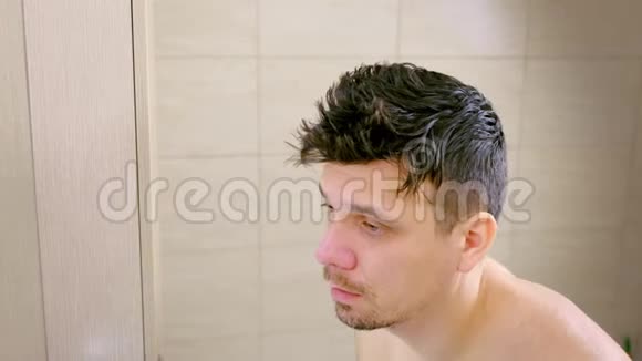 早上一个患有流感的昏睡的青年在浴室里看镜子视频的预览图