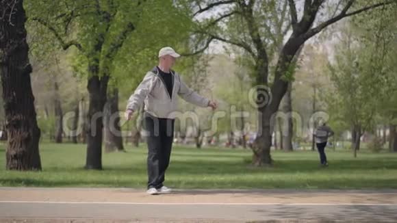 小男孩穿着格子衬衫在公园里滑旱冰爷爷抓住他拥抱主动休闲视频的预览图