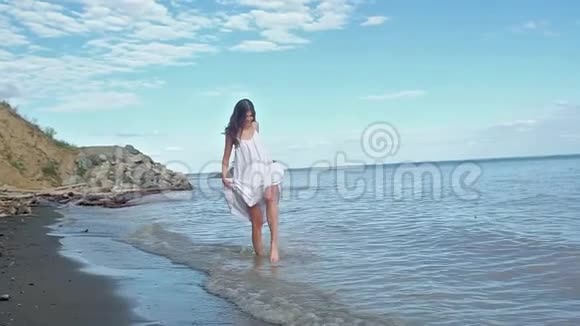 穿着夏装的赤脚女孩在海滩上散步玩得开心吐温创造飞溅视频的预览图