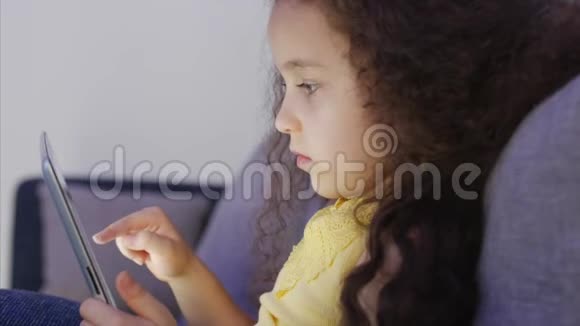 一个白种人可爱的孩子一个小女孩一个孩子的脸上贴着一个平板电脑看着张照片的夜景画像视频的预览图