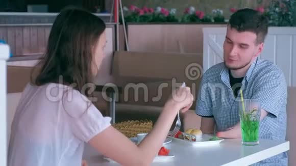 两只截肢的残肢手的残疾男子在咖啡馆里和女人约会吃面包视频的预览图