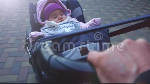 平静的8个月大的女婴睡在户外婴儿车在寒冷的天气舒适的帽子和冬天的整体步行视频的预览图
