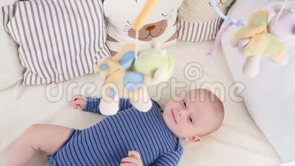 可爱快乐6个月小男孩躺着玩小男孩看着他的玩具视频的预览图
