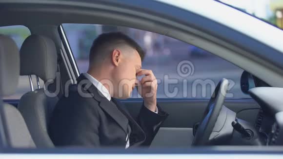 精疲力竭的男性穿着正式西装坐在驾驶座上很大工作过度视频的预览图