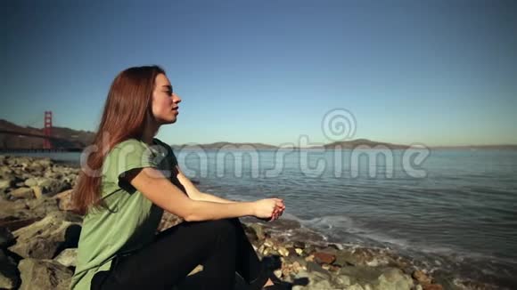 坐在金门大桥旁岩石上的女人视频的预览图