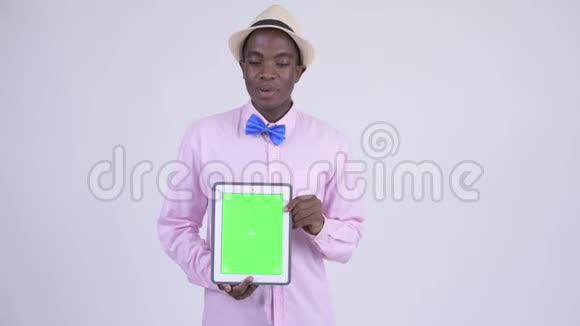 年轻快乐的非洲游客一边说话一边展示数字平板电脑视频的预览图