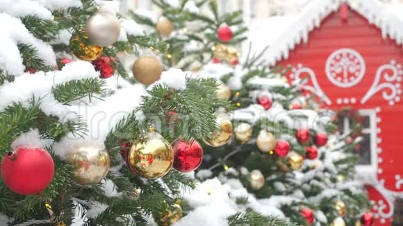 金色和红色的墙挂在圣诞树上上面覆盖着雪和红色的姜饼屋美丽的装饰视频的预览图