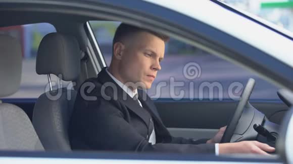 紧张的西装男坐在驾驶座上打电话上班迟到视频的预览图