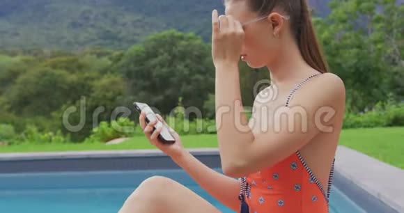 穿泳装的女人在后院用手机视频的预览图