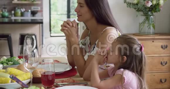 母亲和女儿在餐桌前祈祷视频的预览图