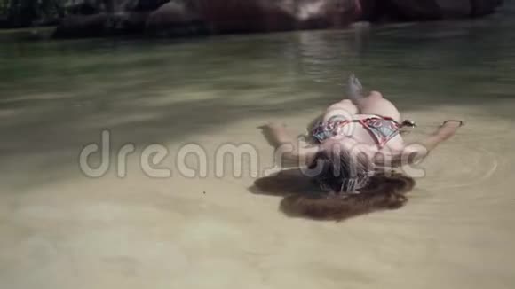 塞舌尔普拉斯林岛漂亮的女孩躺在背上干净的水中放松地球上的天堂旅游视频的预览图