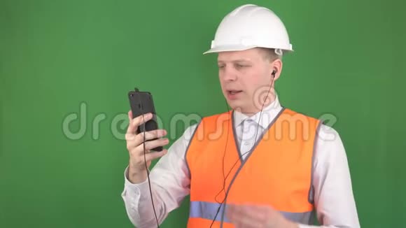 年轻的白种人男老板在工地上和顾客一起用耳机打电话视频通话视频的预览图