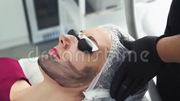 美容诊所碳面剥离手术中戴防护眼镜的年轻女性视频的预览图