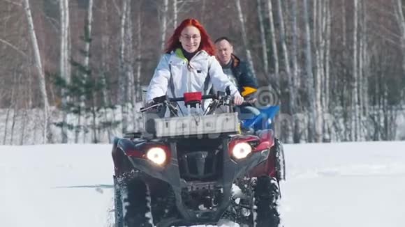 穿着冬装的男女在森林里骑着雪地摩托视频的预览图
