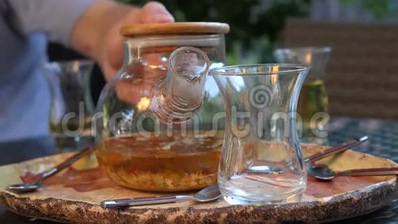一个人把热茶从玻璃茶壶倒入一个透明的杯子里草药茶视频的预览图