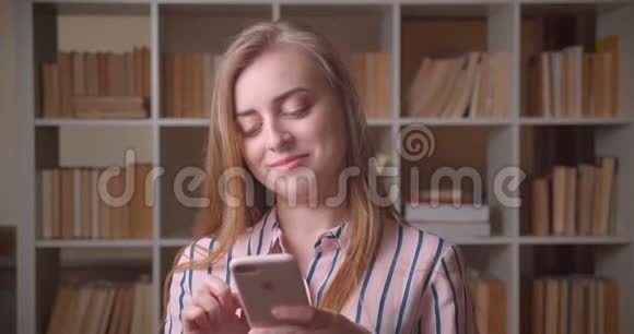 在大学图书馆打电话给年轻漂亮的白种人女学生的特写照片视频的预览图