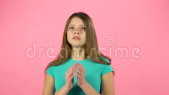 小女孩害怕把她的脸藏在粉红背景的工作室里视频的预览图