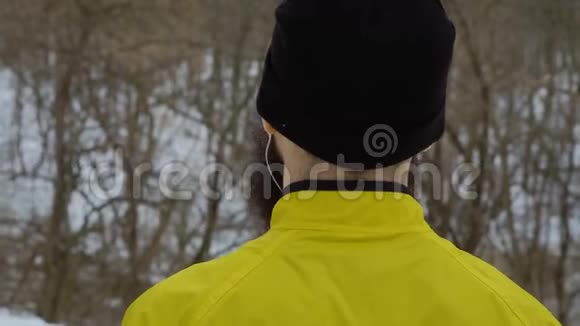 戴耳机的留胡子男子站在冬林后景特写视频的预览图