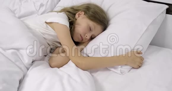十岁的女孩一头金发睡在枕头上的白床上视频的预览图