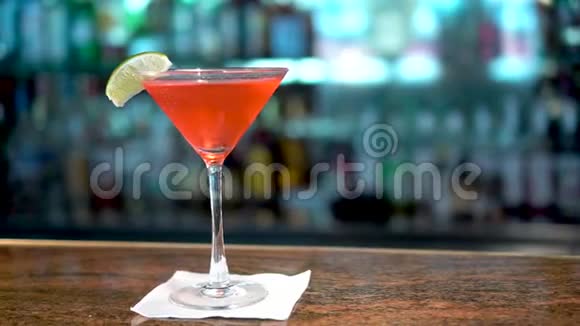 酒吧柜台上的马提尼酒杯中的红色饮料世界大都会鸡尾酒的特写视频的预览图