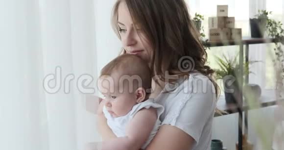 女人抱着小女儿从窗户往外看视频的预览图
