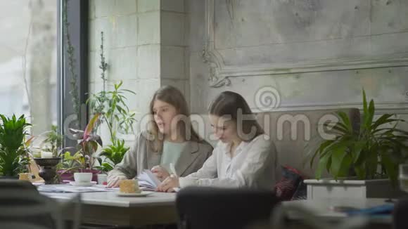 两个商务女性在咖啡馆里讨论商务项目和喝咖啡视频的预览图