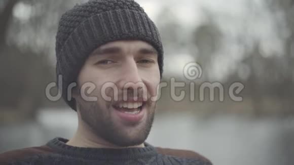 站在户外的一个戴着温暖帽子的有胡子自信微笑的嬉皮士的肖像男人在周末放松视频的预览图