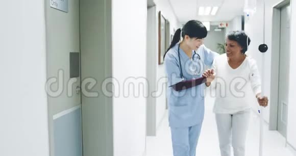年轻女医生帮助老年病人走医院走廊4k视频的预览图