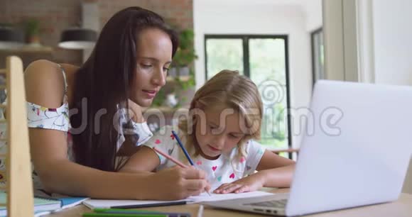母亲在舒适的家里帮女儿做作业视频的预览图