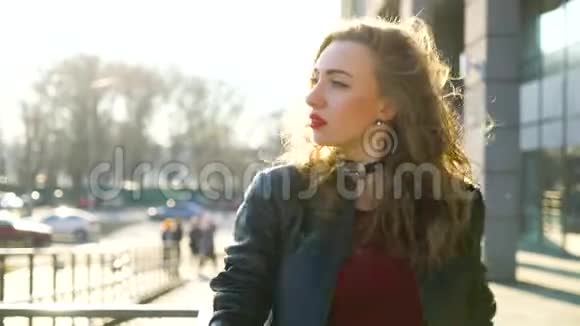 在阳光明媚的城市街道上一位金发美女戴着红色口红的肖像视频的预览图