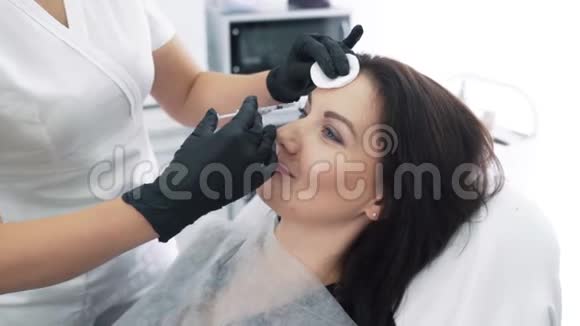 特写女性面部及美容师用注射器双手进行面部美容注射动作缓慢视频的预览图
