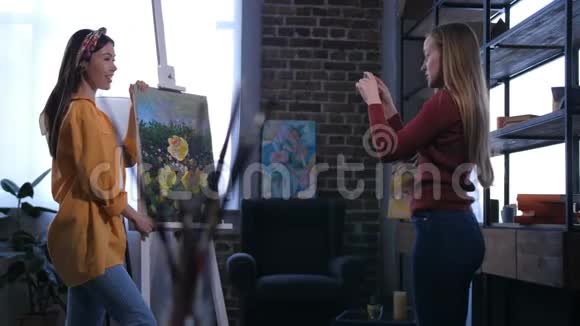 漂亮的女画家摆着画好的艺术品视频的预览图