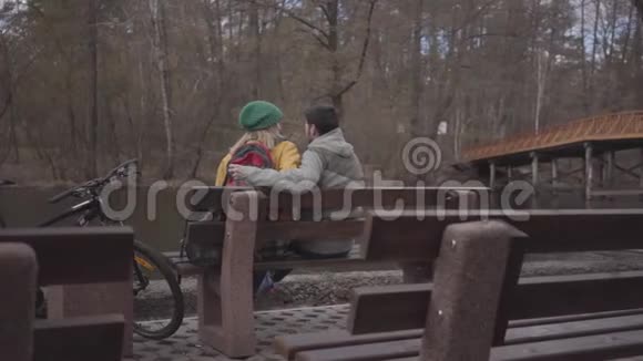 在河岸的春天公园里几个背包游客坐在长凳上有胡子的人视频的预览图