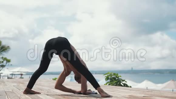 运动男子做瑜伽运动站在头上大海和手掌在背景上视频的预览图