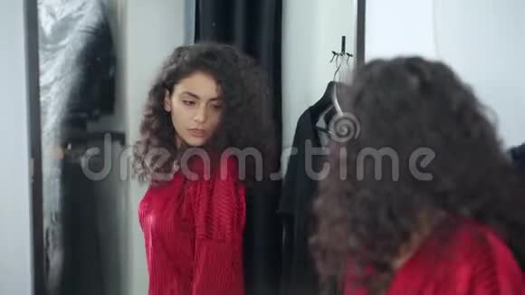 十几岁的女孩正在商店里照镜子穿着红色的长袍视频的预览图
