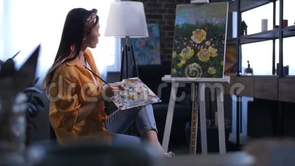 年轻的女画家欣赏她的画视频的预览图