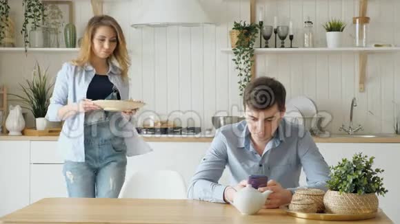 女孩把饼干杯子放在桌子上男人看电话视频的预览图