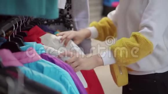 女人的手在服装店里用运动保暖夹克触摸衣架视频的预览图