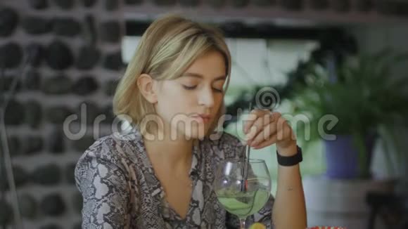 伤心沮丧的年轻女子坐在咖啡馆喝鸡尾酒视频的预览图