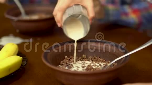 孩子们把杯子里的牛奶倒进碗里的麦片粥愉快的友好家庭享受早餐视频的预览图