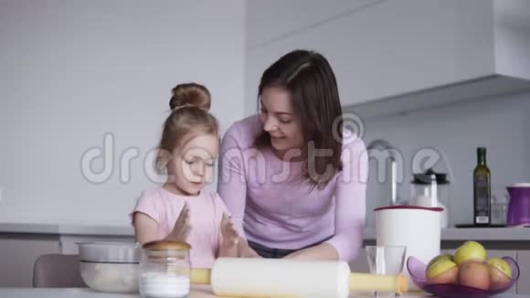 可爱的小女孩和她漂亮的妈妈在厨房里揉面团的时候玩得很开心笑得很开心女孩触摸视频的预览图