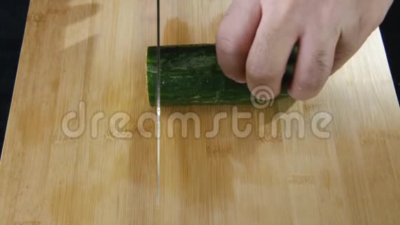 在餐厅的厨房里人的双手慢慢地在木板上切一根新鲜黄瓜股票视频的预览图